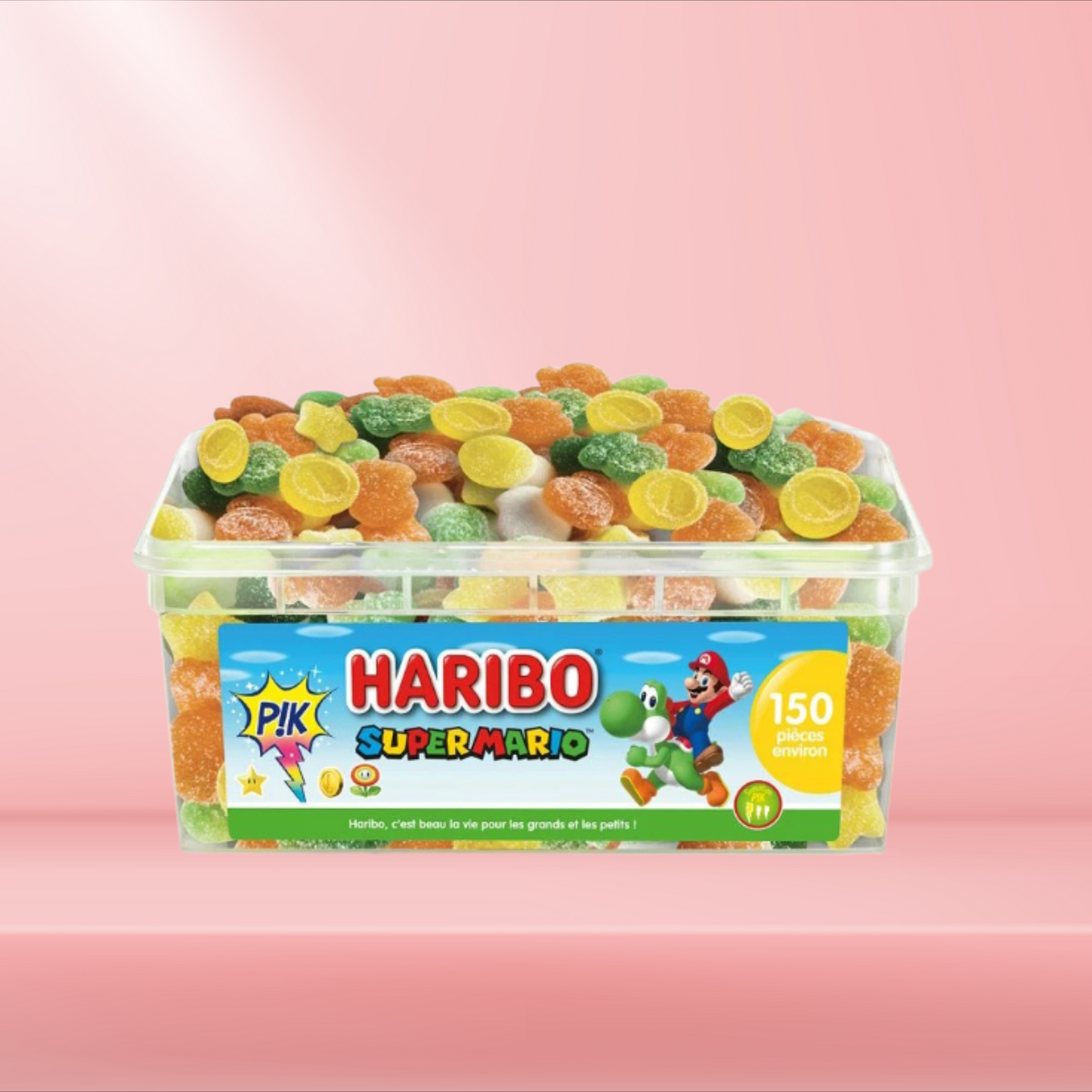 Boîte de bonbons Haribo Super Mario sur fond rose, mélange fruité et coloré.