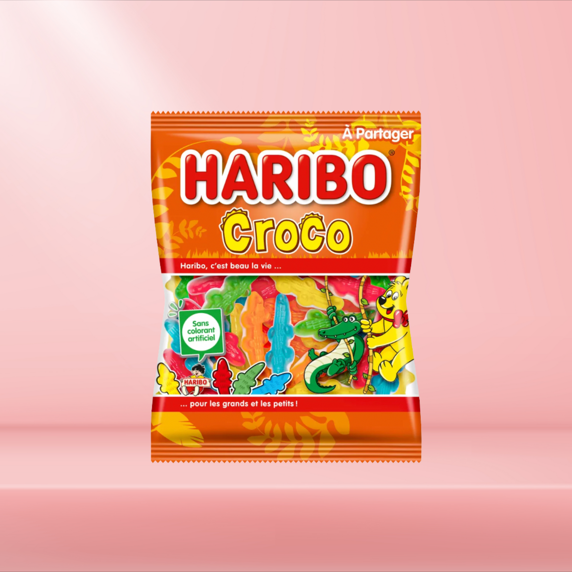 Sachet de bonbons Haribo Croco, bonbons gélifiés en forme de crocodiles aux saveurs fruitées, sur fond rose.
