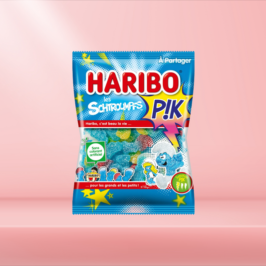 Sachet de bonbons Haribo Schtroumpfs Pik, bonbons fruités et acidulés inspirés des Schtroumpfs, sur fond rose.