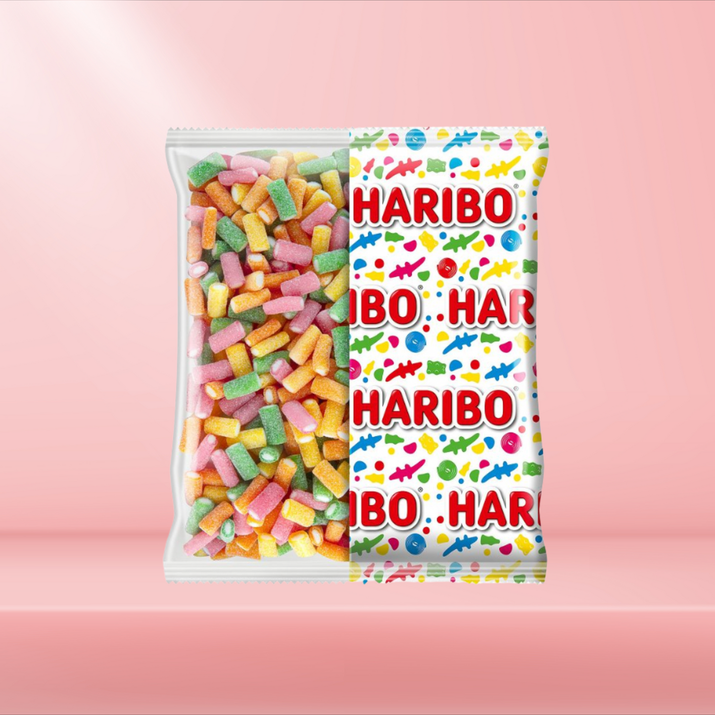 Boîte de bonbons Haribo Rainbow, bonbons gélifiés multicolores acidulés, posée sur fond rose.