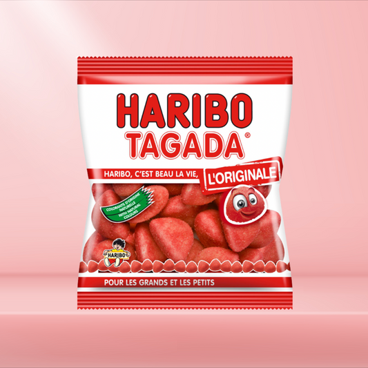 Sachet de Fraises Tagada Haribo, célèbre bonbon rouge sucré à la fraise, sur fond rose.